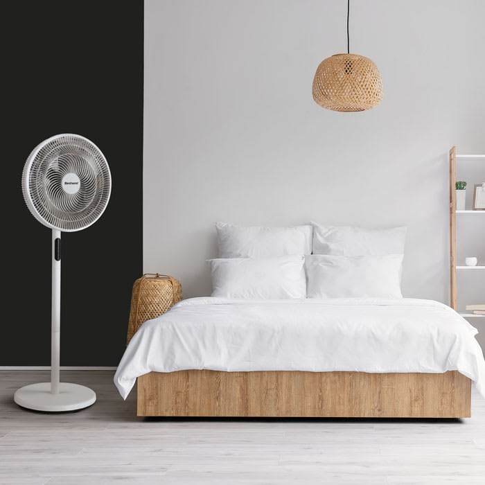 Ventilador pedestal DC Bestherm junto a la cama en un dormitorio
