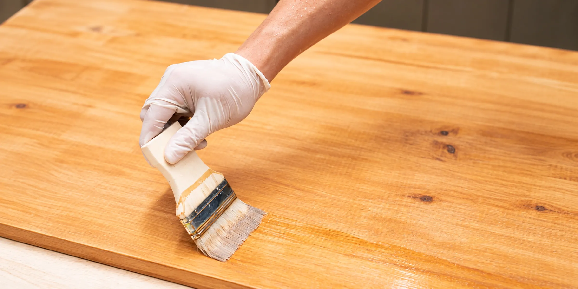Aplicación de acabado con brocha sobre una superficie de madera