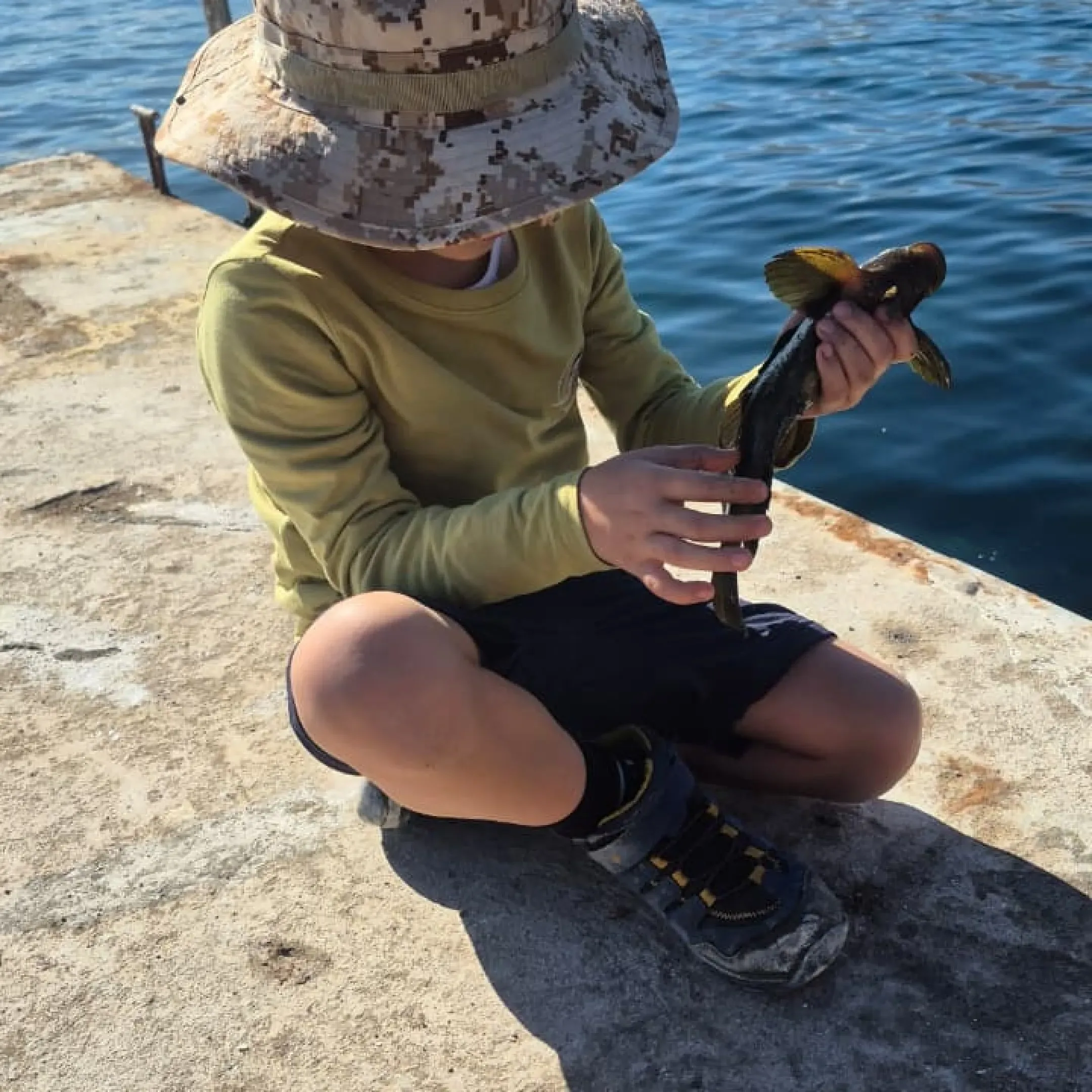 Niño sosteniendo un pequeño chalaco capturado pescando desde el muelle de Taltal