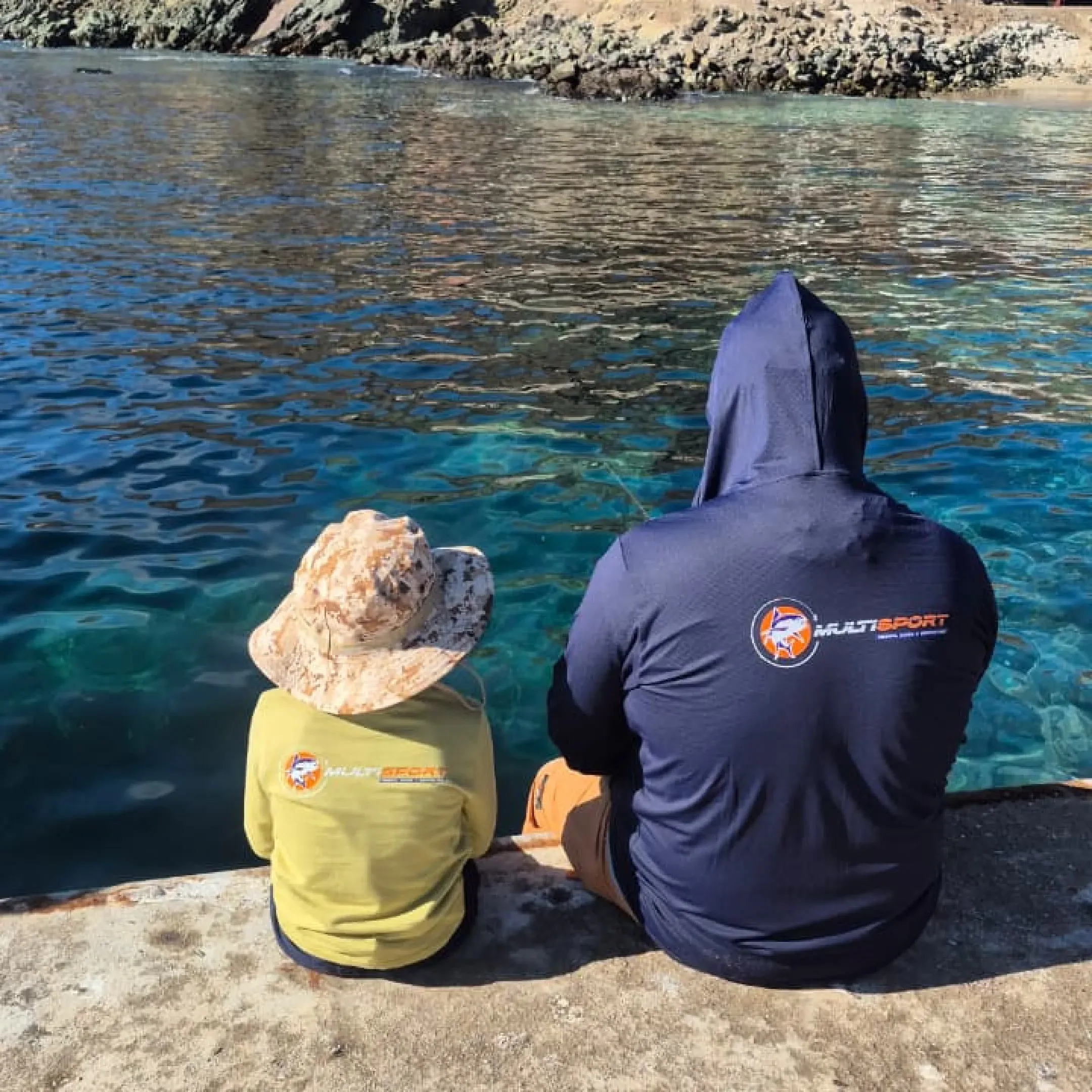 Padre e hijo sentados en el muelle de Taltal mirando hacia el mar