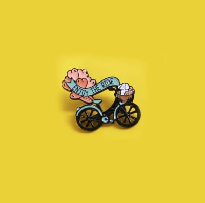 Pin esmaltado diseño de perro poodle en una bicicleta