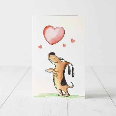 Tarjeta de San Valentin con diseño de perrito persiguiendo un corazón